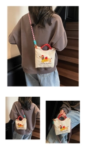 Detail of embroidered dachshund puppy and red handles on a cream canvas bucket bag