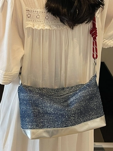 Polka dot denim shoulder bag with red rope strap and silver trim on female model