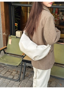 Detail of white lychee texture leather hobo bag with silver metallic buckle on a shoulder strap