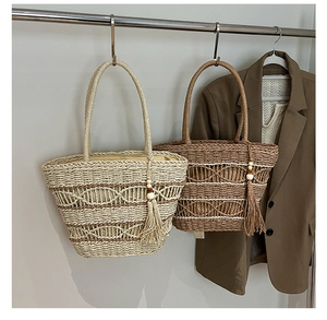 Detailed close-up of handmade straw tote bags with hollow weave pattern and tassel charms