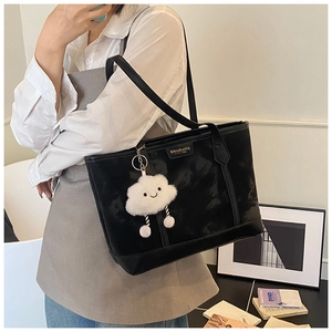 Close-up of black tote bag with gold brand lettering and a white fluffy cloud charm