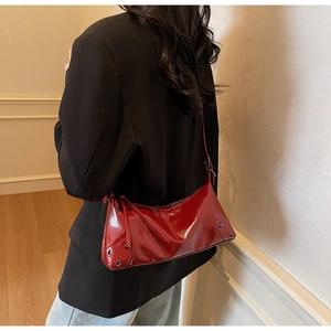 Detail der roten Lackleder-Schultertasche mit silbernen Ösen und trendigem Quasten-Zipper