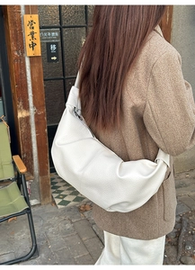 Close-up of large pleated croissant bag in premium white lychee grain leather finish