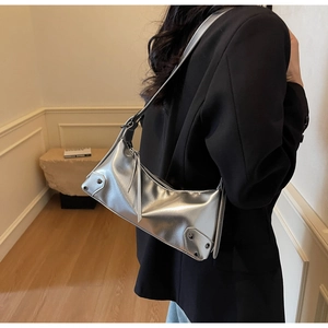 Detail der silbernen Metallic-Unterachseltasche mit schwarzen Nieten und Quasten
