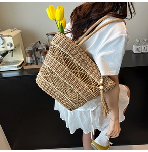 Detail of hand-woven straw tote bag featuring hollow geometric pattern and tassel decor