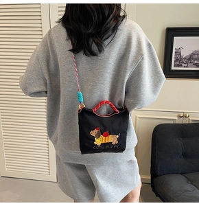 Detail of woven cotton rope shoulder strap on black embroidered dachshund bucket bag
