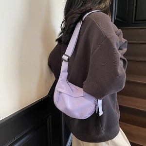 Detail view of a light purple crescent crossbody bag featuring smooth nylon fabric and strap