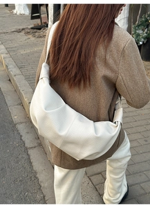 Detail of white pleated crescent bag with lychee pattern texture and knotted strap