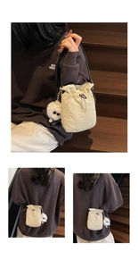Detail of off-white drawstring bucket bag with plush monster charm and black thin strap
