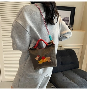 Detail of cute dachshund embroidery on a brown canvas bucket bag with colorful woven strap
