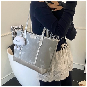 Detail of silver tote bag featuring cloud texture and white plush cloud pendant accessory