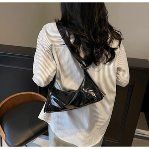 Detail der schwarzen Lackleder-Tasche mit Metallnieten und Ösen im coolen Punk-Stil
