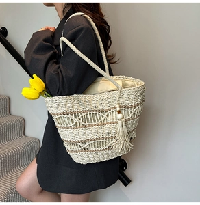 Detail of hollow woven pattern on straw tote bag with elegant tassels and shoulder strap