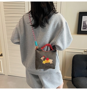 Detail of embroidered dachshund puppy on dark brown canvas bucket bag with rope handle
