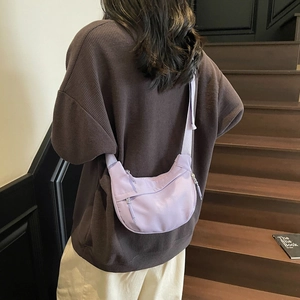 Light purple nylon crescent crossbody bag shown with adjustable strap on model