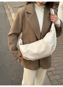 Detailed texture of white crescent bag in lychee leather grain on casual outfit