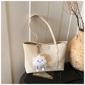 Close-up of a cream tote bag with a cloud pendant and branded logo on the front