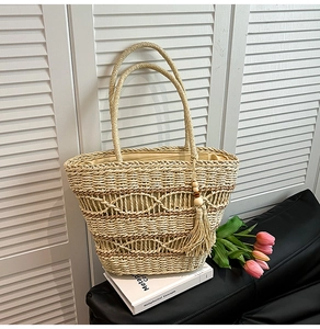 Macro detail of hand-woven straw tote with elegant hollow patterns and tassel decoration