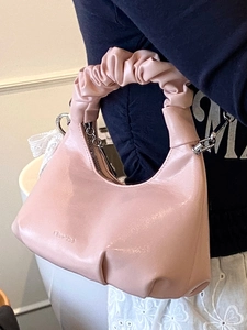 Sac demi-lune rose avec poignée froncée et finition brillante porté par modèle