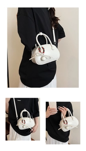 Detail of cream white mini Boston bag featuring ribbon bow and colorful bead chain charm