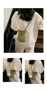 Detail of green drawstring bucket bag with a cute white plush monster charm