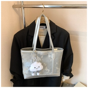 Detailed view of silver tote bag texture with cute plush cloud charm on a garment rack