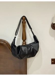 Detailed view of black textured dumpling bag with pleated design and metal hardware