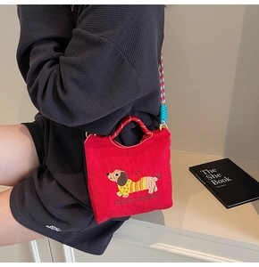 Detail of red canvas bucket bag with cute dachshund embroidery and colorful woven strap