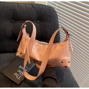 Nahaufnahme der rosa glänzenden Leder-Achseltasche mit Metallnieten und breitem Riemen