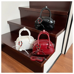Three glossy bowling-style handbags in black, white, and red with decorative bead charms