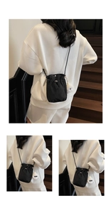 Close-up of black drawstring crossbody bag with a white plush doll charm detail
