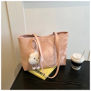 Close-up of pink shoulder bag with smiley cloud charm on a dark wooden surface