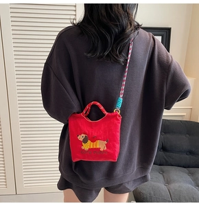 Detail of red canvas bucket bag featuring cute puppy embroidery and colorful woven strap