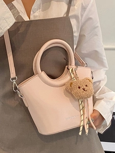 Borsa a secchiello rosa minimalista con manico circolare e ciondolo a orsetto