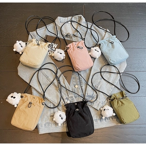 Flat lay of small nylon crossbody bags in six colors with plush monster charms on denim