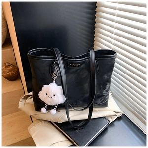 Detail of black marble-textured tote bag with gold logo and fluffy cloud charm accessory