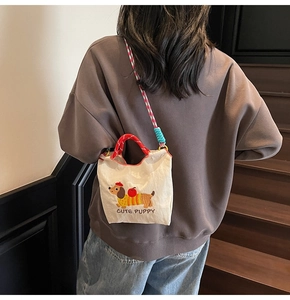 Detail of cute dachshund embroidery on canvas bucket bag with colorful woven strap