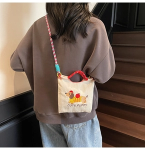Detail of cute dachshund dog embroidery and red checkered strap on canvas bucket bag