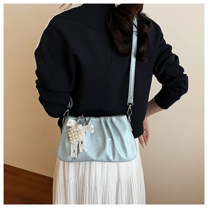Détail du sac nuage plissé bleu clair avec grappe de perles et nœud en dentelle blanche