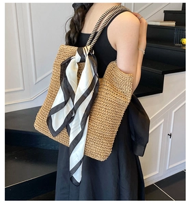 Close-up of casual straw tote bag featuring woven texture and a stylish striped scarf detail