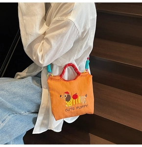 Detailed close-up of orange embroidered dachshund bucket bag with woven rope handles