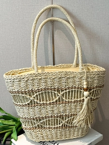 Large beige straw tote bag with hollow patterns and tassel for beach vacations
