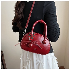 Detail of burgundy bowling bag with sleek leather texture and bead charm on white dress