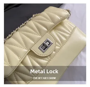 Macro shot of silver metal twist-lock and quilted texture on beige crossbody bag