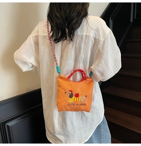 Detail of cute dachshund embroidery and colorful braided handle on orange canvas bucket bag