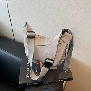 Close-up of light grey nylon crescent bag with adjustable strap and side zipper pocket