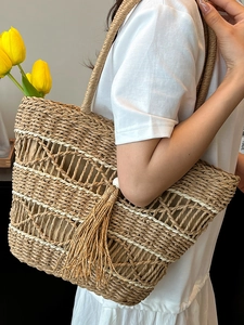 Handmade woven straw tote bag with large capacity, hollow texture and tassel detail