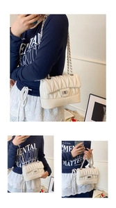 Detail view of a cream quilted crossbody bag with silver metal chain and twist-lock