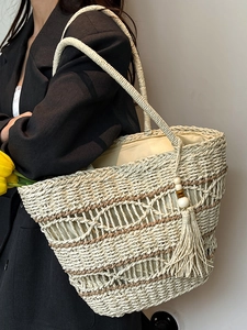 Handmade woven straw tote bag with tassel detail and hollow pattern for beach vacation