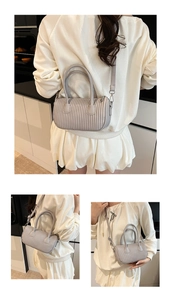 Detailed views of light grey pleated cylinder bag with top handles and adjustable strap